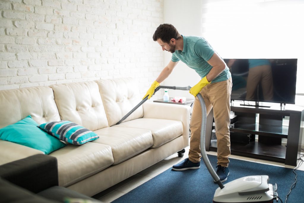 person cleaning couch with steam cleaner